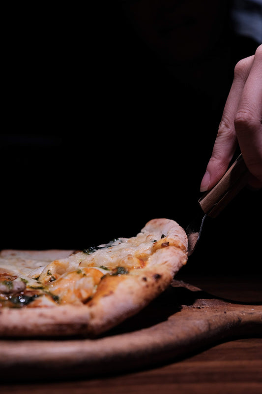 A pizza being sliced and served. By Liam Nguyen via Unsplash