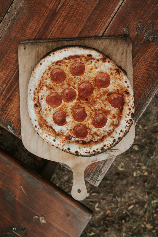 A pepperoni pizza on a wooden peel. By Mariusz Słoński via Unsplash