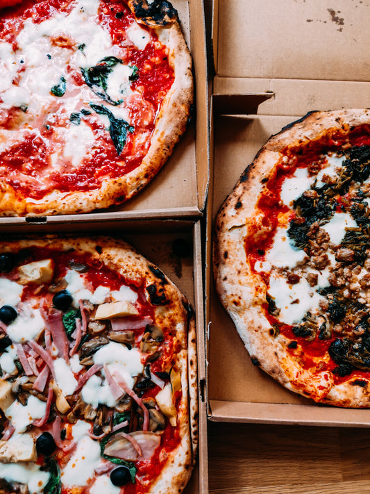 three pizzas in boxes with various toppings. By Unleashed Agency via Unsplash